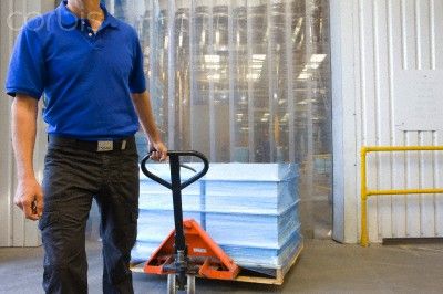 Worker pulling inventory on hand truck on loading dock