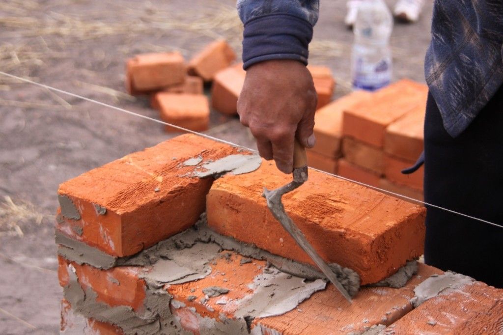 Muratore in a elmetto protettivo costruzione mattone