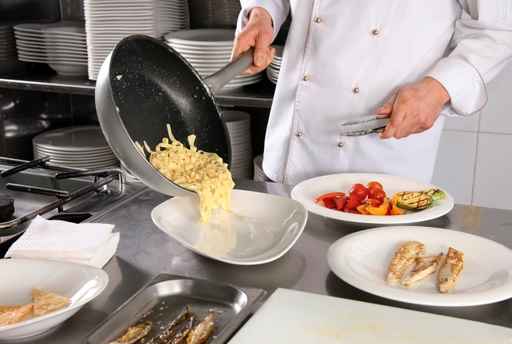 Chef preparing pasta on professional kitchen in restaurant